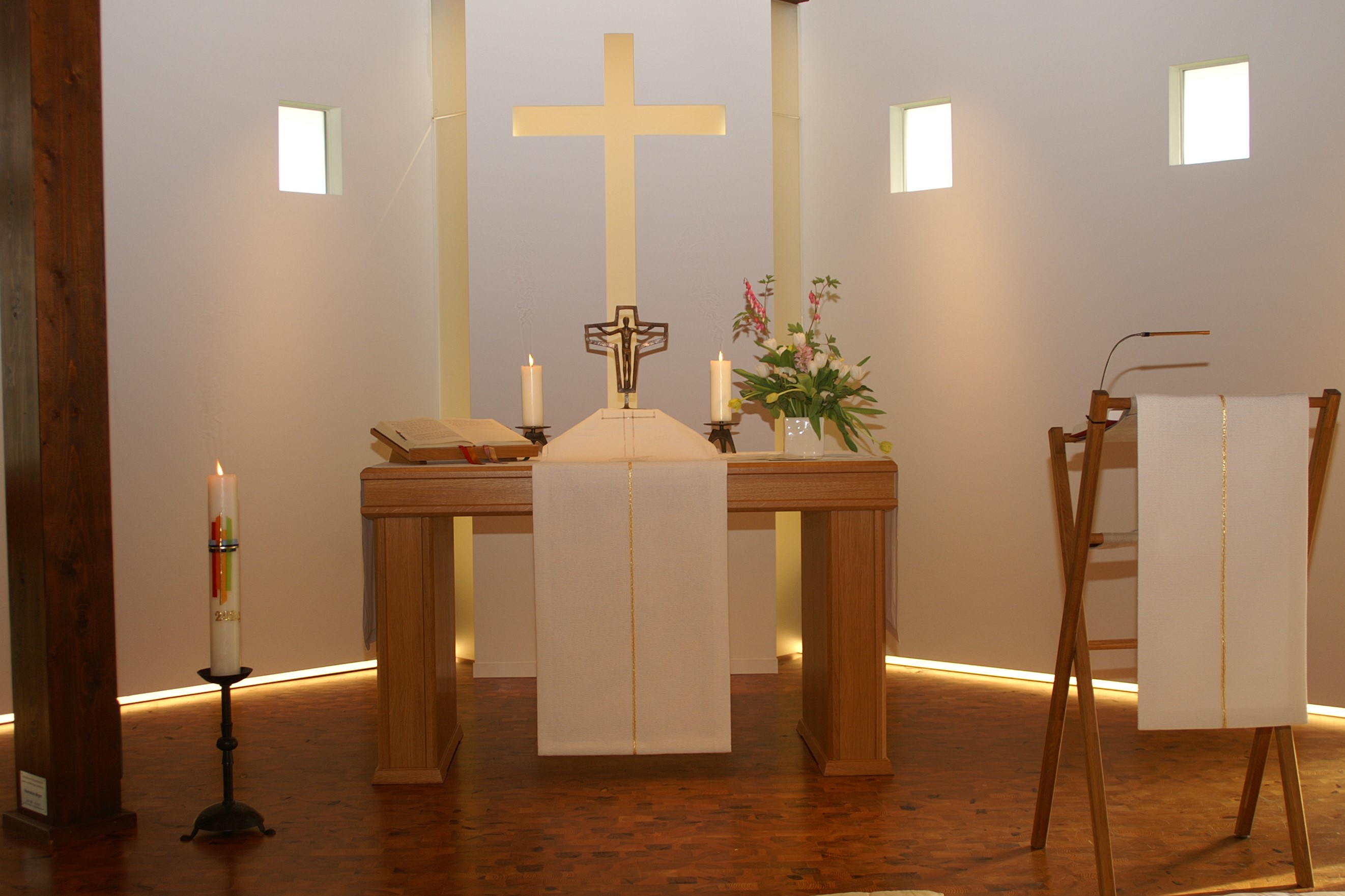 Gesamtbild des Altarraums der Holzkirche mit Lesepult und Kerze